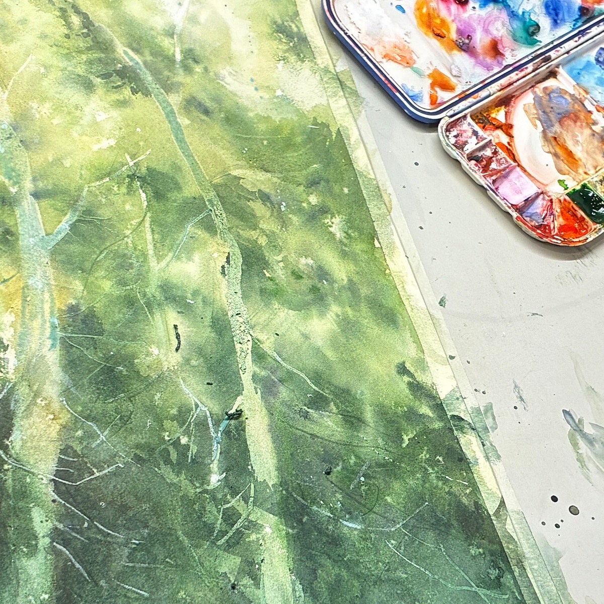 Green watercolour wash beside an open paint palette